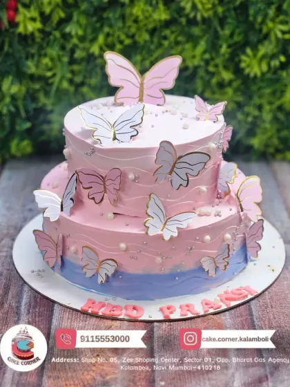A beautiful two-tier butterfly cake in shades of pink and blue. The paper butterflies seem to flutter around the cake, creating a light and airy design.