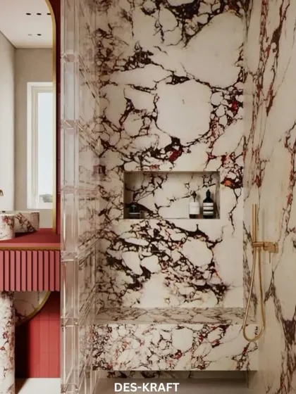 A close-up of the shower niche, seamlessly carved into the striking red and white marble wall, combining practicality with high-end design.