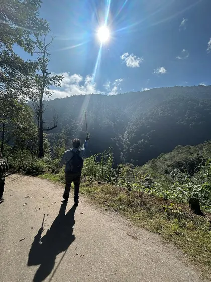 The first day of a trek is always filled with excitement. A trekker points towards the sunlit mountains ahead on the Sandakhphu-Phalut trail, ready for the adventure.
