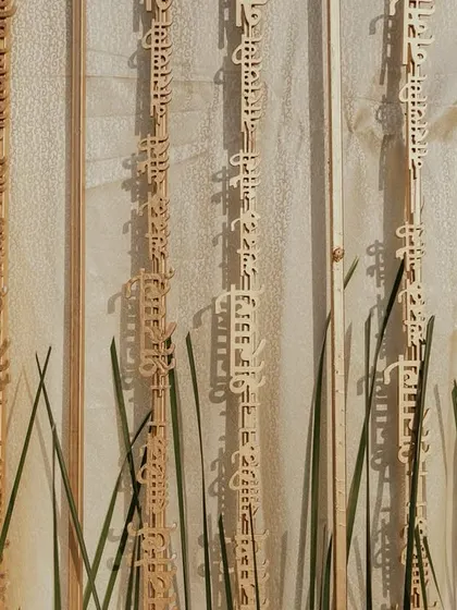 A unique backdrop detail from Aashvi and Akash's wedding, featuring hanging wooden panels with Sanskrit verses, adding a deeply personal and spiritual touch to the decor.