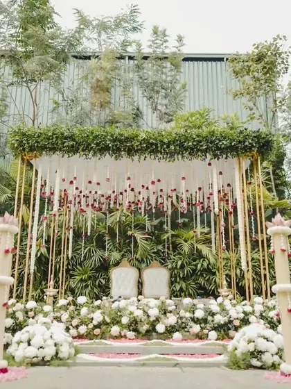 An elegant mandap setup featuring a canopy of hanging jasmine and rose garlands, creating a fragrant and visually delicate space for a traditional morning ceremony.