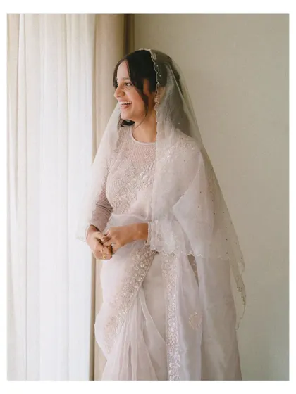 A candid shot of a bride sharing a joyful laugh by the window. The natural light and her spontaneous smile capture the happiness and excitement of her wedding day.