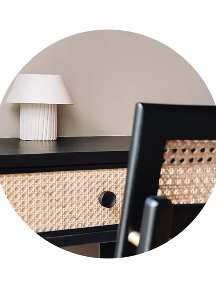 A close-up of the custom-designed study desk. The combination of black burnt wood and natural cane webbing creates a beautiful textural contrast. The minimalist white lamp completes the clean, modern look.