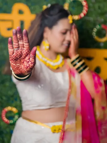 Another artistic shot highlighting the bride's henna-stained hand against her vibrant Haldi outfit.