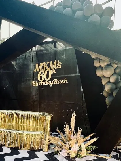 This 60th birthday bash had a chic black, gold, and white theme. The geometric stage, fringed gold sofa, and chevron-patterned floor created a sophisticated and modern look for the milestone celebration.