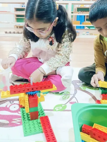 Two children collaborate on a building project, figuring out how to create a balanced seesaw mechanism. They are learning about levers and pivots through teamwork.