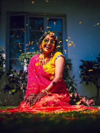 A bride covered in turmeric and flower petals, relaxing on the grass during her Haldi ceremony. A moment of colorful bliss.