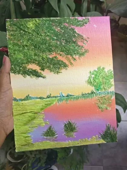 A small, impressionistic landscape painting with a colorful sunset reflected in the water.