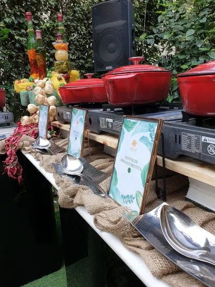 A rustic, picturesque live cooking station set up in a garden. We used burlap runners, wooden crates, and bright red cast-iron pots to create a charming and inviting atmosphere for this outdoor event.