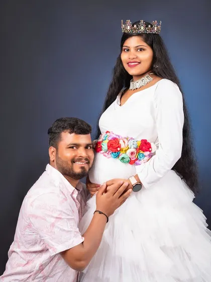 A beautiful couple's portrait from a maternity shoot. She is wearing our white ruffle gown with a floral belt and crown.