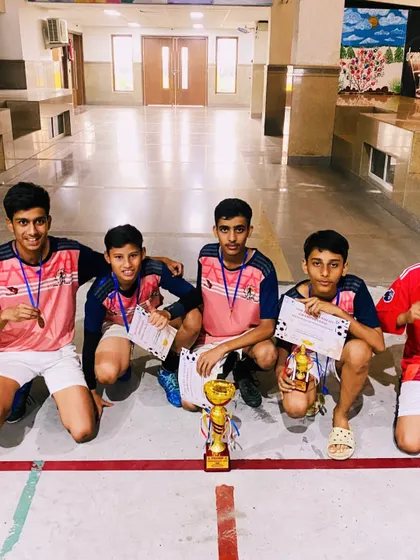 The winning Under-15 team kneels for a group photo with their trophy, a symbol of their collective effort and success.
