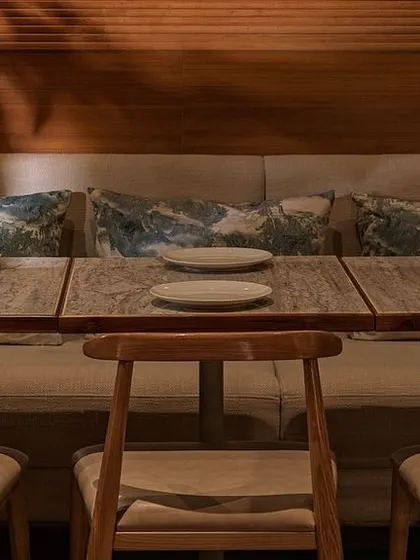 A close-up of the table setting at Biergarten. The combination of a stone tabletop, simple wooden chairs, and soft upholstered seating reflects our focus on natural, high-quality materials.