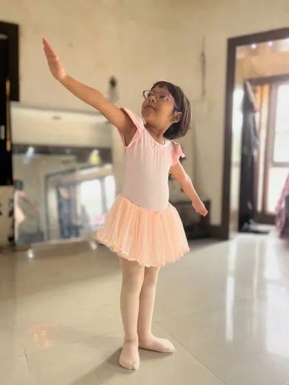A young student practices her poses in a pink leotard and tutu. Proper attire is encouraged in my ballet classes to help with movement and discipline.