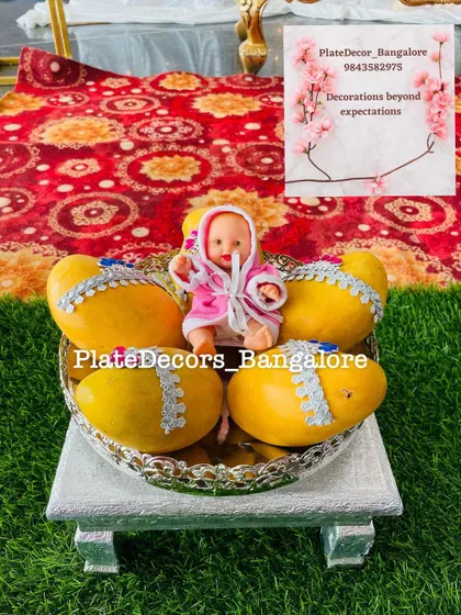 A silver platter with decorated mangoes and a baby doll, set on a small silver stand (manai). This elevates the gift and makes it a beautiful centerpiece.