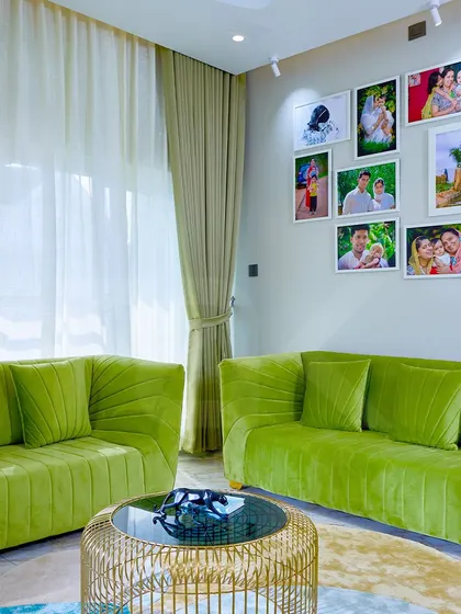 The full view of the green velvet sofa set, complete with a modern gold-caged coffee table.