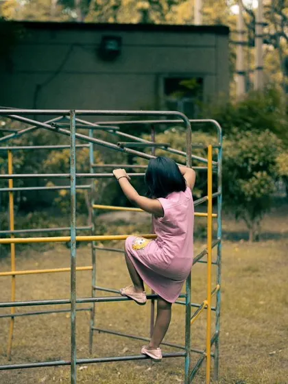 A shot from the back as she explores the climbing frame. This perspective tells a story of independence and adventure.