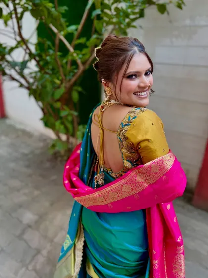 A beautiful back profile showcasing the elegant hairstyle and the backless blouse design. The makeup on the side profile looks clean and sharp.