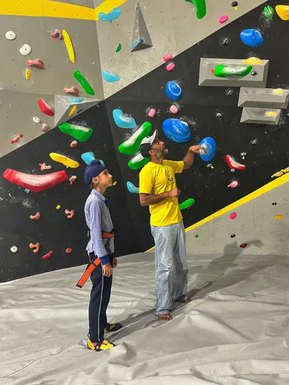 A coach explains the nuances of a bouldering problem to a new climber. We believe in hands-on instruction to help you understand body positioning and movement, making your first climbing experience a positive one.