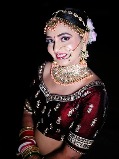 A close-up portrait of a smiling bride, highlighting her intricate nath (nose ring) and bridal makeup.