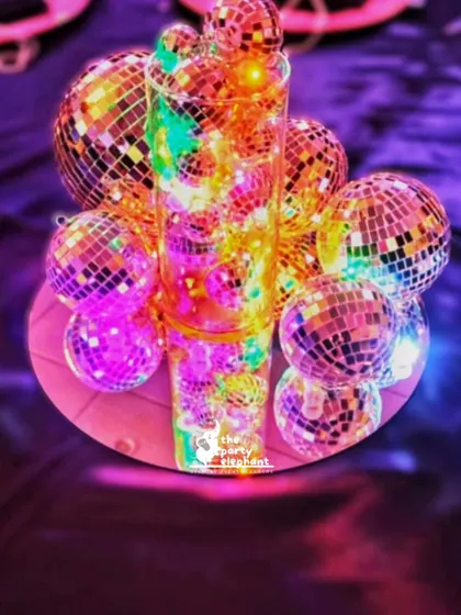 A creative centerpiece for the neon disco party, made from a cluster of mini disco balls illuminated with colorful lights, perfectly capturing the theme.