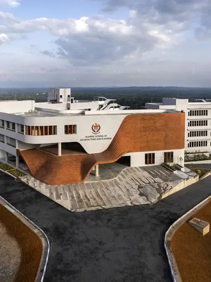The Manipal School of Architecture & Planning, where the facade becomes a fluid, brick-clad gesture. This undulating form creates a welcoming, doorless entrance, tucking the main access below and allowing the steps to become a democratic space for student interaction.