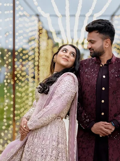 A romantic couple posing at their Sangeet against a backdrop of fairy lights, creating a magical and dreamy atmosphere.
