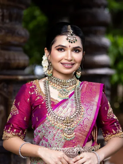 A close-up portrait of a bride wearing a heavy silver-finish set with intricate designs. The matching nose ring and maang tikka add to the overall grandeur.