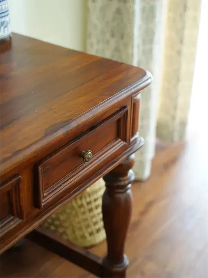 A close-up of the ornate study desk, showing the detailed craftsmanship of the turned legs and the rich finish of the solid wood.