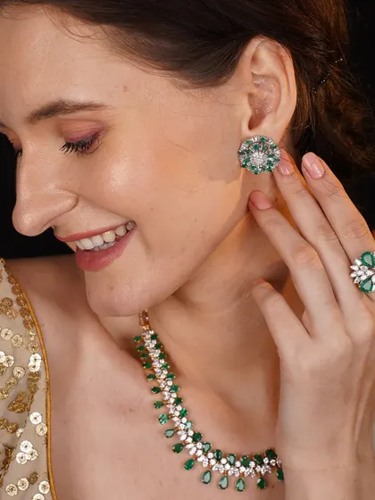 A model adorned in a beautiful diamond and emerald set, including a necklace, earrings, and ring. The vibrant green of the emeralds provides a stunning contrast to the sparkling diamonds.