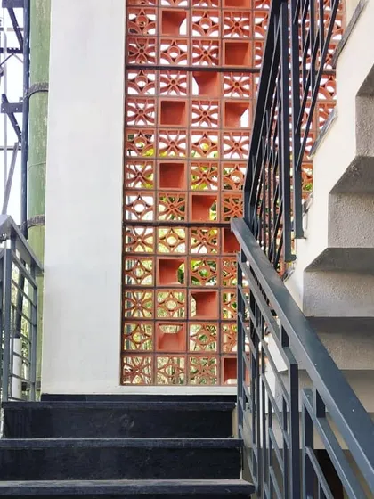 A staircase is more than just a way to get from one floor to another; it's a design opportunity. Here, a terracotta jaali screen acts as a feature wall, allowing for ventilation and creating beautiful light patterns while adding a distinct Indian artisanal touch to the home.