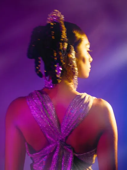 A back profile shot focusing on the intricate hairstyle and the play of light on the glittery outfit.