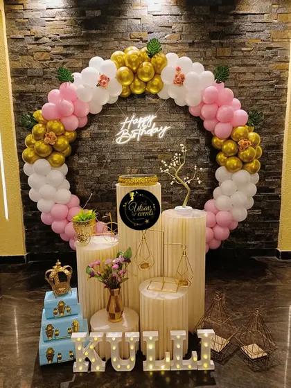 A beautiful ring-themed birthday decor in pink, white, and gold. The balloon arch, neon sign, and plinth arrangement create an elegant photo corner.