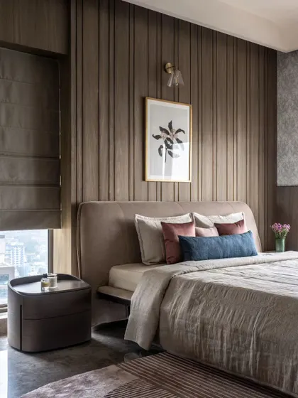 A bedroom in the Skyward Residence featuring a curved ceiling cove that washes the wall in soft, indirect light. The wood-paneled wall adds texture and warmth to this cozy, high-rise bedroom.