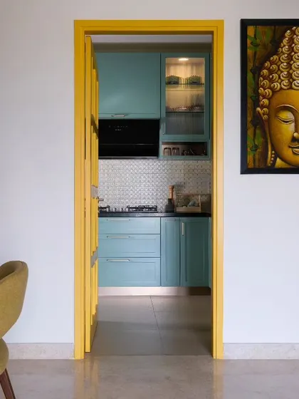 A key client request was a yellow door for the kitchen. We designed this French door with a sunshine-yellow frame, creating a cheerful focal point that allows light to flow freely and complements the tranquil green tones of the kitchen cabinetry.