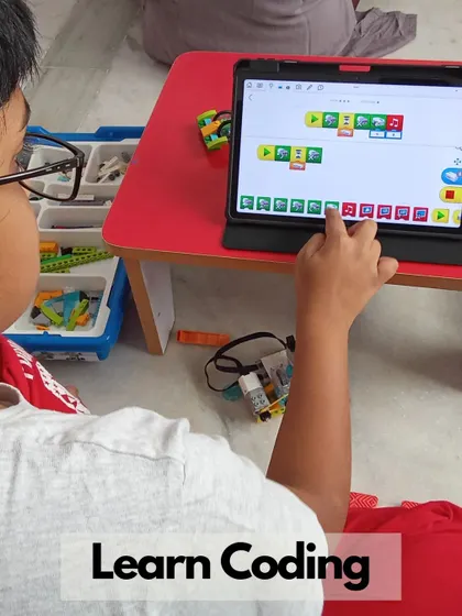 A close-up of a student's hands on a tablet, demonstrating the intuitive, block-based coding interface we use for beginners.