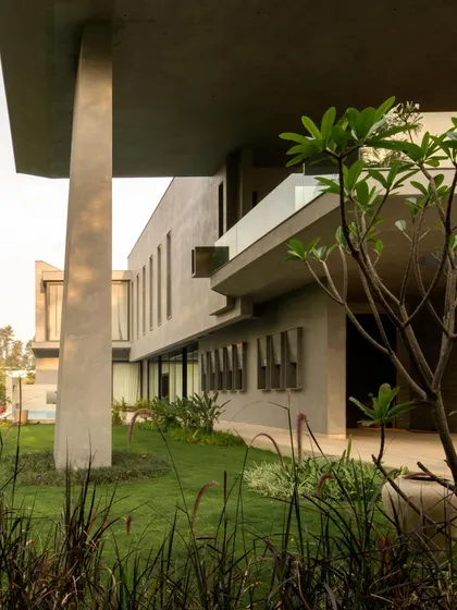 Views of the home from the garden, showing how the monumental concrete forms are softened by the surrounding greenery. The design creates a constant interplay between the architecture and the landscape.