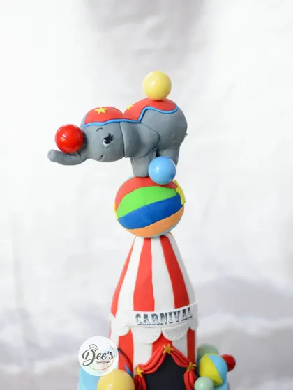 The incredible balancing elephant topper is the star of this circus cake, showcasing gravity-defying cake artistry.