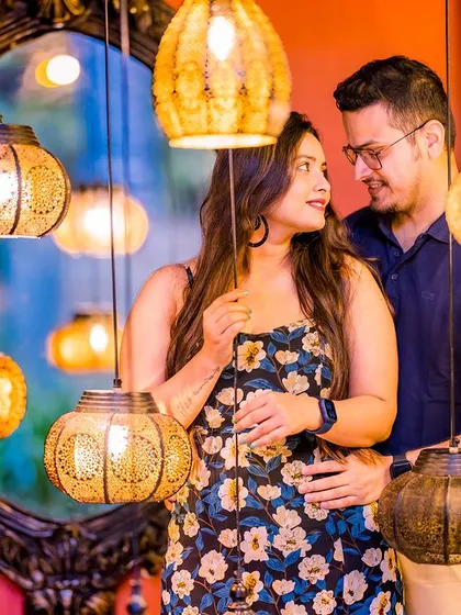 A creative and intimate shot using hanging lanterns. The couple is reflected in a mirror behind them, adding depth and an artistic touch to this warm, colorful portrait.