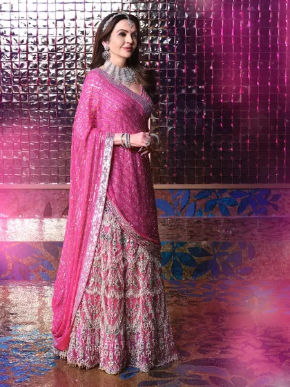 A full-length portrait of Mrs. Nita Ambani from the Sangeet evening. This shot showcases the entire stunning Falguni Shane Peacock ensemble against a textured, iridescent background.