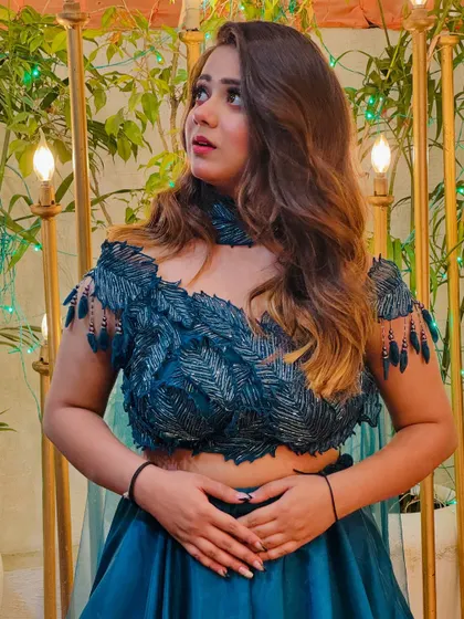 A close-up on the feather-like embroidery of the teal blouse. The details on this piece are what make it a true showstopper.