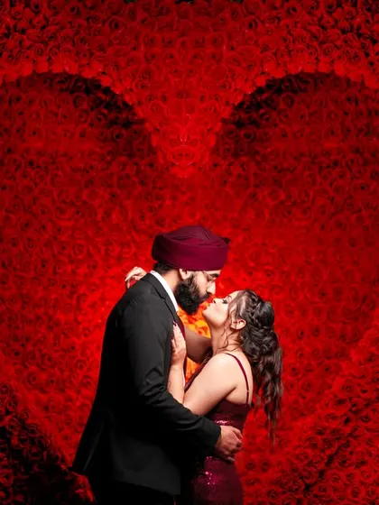An artistic shot using a textured red background to create a giant heart, perfectly framing the couple's kiss.
