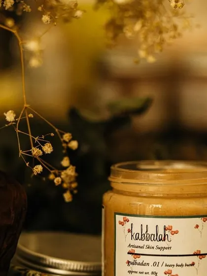 My 'Gulbadan' heavy body butter, surrounded by delicate dried flowers. It’s a versatile product that can be used to deeply moisturize your body or to condition the ends of your hair.