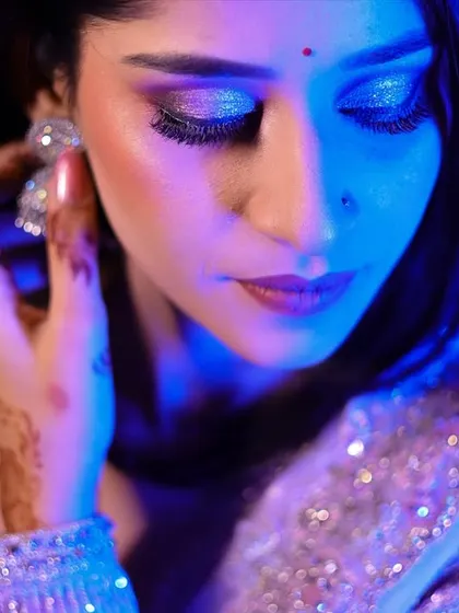 A close-up shot focusing on the bride-to-be's glittery eye makeup and jewelry, using artistic lighting.