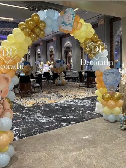 A grand balloon arch with a large teddy bear forms a welcoming entrance for guests.