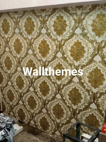 A work-in-progress shot of a large wall being covered in a gold and white damask wallpaper, showing the scale of the project.