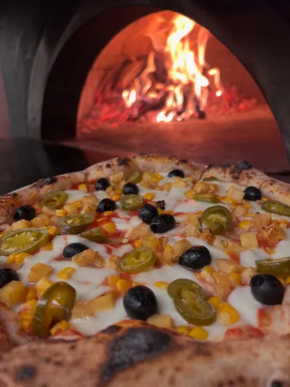 Our Classic Veg pizza, hot from the wood-fired oven. Topped with corn, olives, and jalapeños.