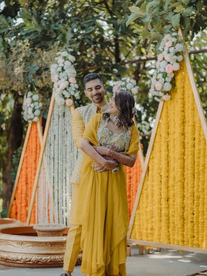A happy couple shares an embrace in front of the modern, geometric Haldi backdrop.