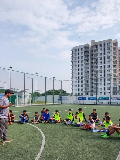 A coach briefs the U-15 team on the field. This session focuses on game strategy and positioning ahead of the upcoming KSFA Youth League.