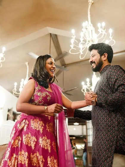 A candid moment of the couple dancing at their indoor engagement party, surrounded by elegant chandeliers.