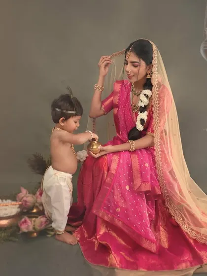 A candid moment between mother and child during a Yashoda-Krishna photoshoot. The mother adjusts her little one's hair in a scene filled with tenderness and cultural beauty.